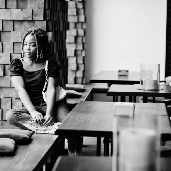Lovely african american woman with dreadlocks in blue stylish jeans at cafe. Beautiful cool fashionable black young girl indoor.